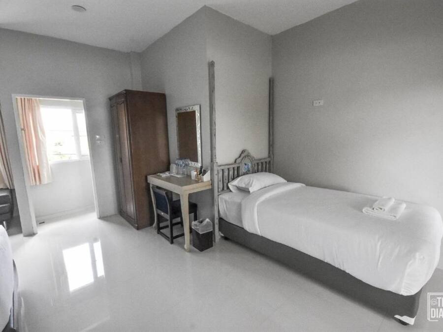 Habitación de hotel con cama, escritorio, armario y espejo.
