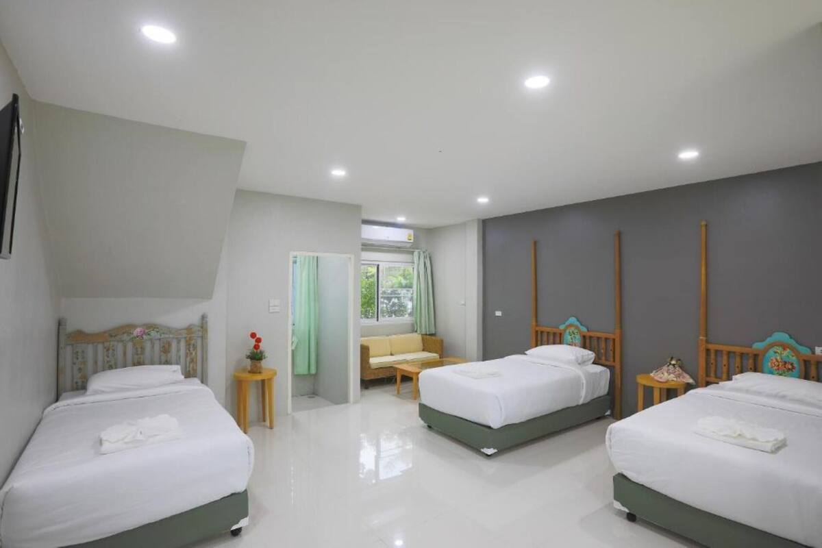 Una habitación de hotel con tres camas, un sofá y una pequeña mesa.