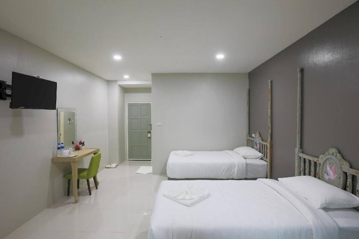 Habitación de hotel con dos camas, un escritorio con silla, un televisor y una puerta que da a otra habitación.