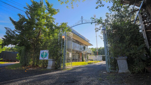 Een gebouw met een poort en een grindpad, omgeven door bomen.