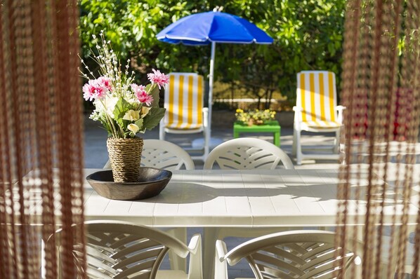 A table with a woven bowl and flowers, surrounded by white chairs, under a blue umbrella. - House / Villa - Castellammare del Golfo (Castellammare del Golfo)