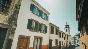 Eine enge Straße mit Gebäuden im traditionellen Baustil, darunter ein Glockenturm.