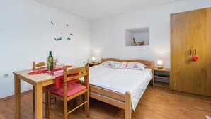 A bedroom with a wooden bed, a wooden desk with a chair, a nightstand, a wardrobe, and wall decorations including a shelf with fruit and a wall art of birds. - Cozy apartment in Bakar with WiFi (Bakar)