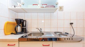 A compact kitchen with a sink, a coffee maker, and a toaster. There are cabinets with red handles and a shelf above the sink. - Cozy apartment in Bakar with WiFi (Bakar)