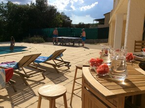 A poolside area with lounge chairs, a table with watermelon and drinks, and a ping pong table. - Beautiful Provençal house with great swimming-pool (Ginasservis)