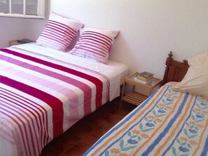 A bedroom with two beds, one with a striped bedspread and the other with a floral pattern. There is a nightstand with a book and a lamp. - Beautiful Provençal house with great swimming-pool (Ginasservis)