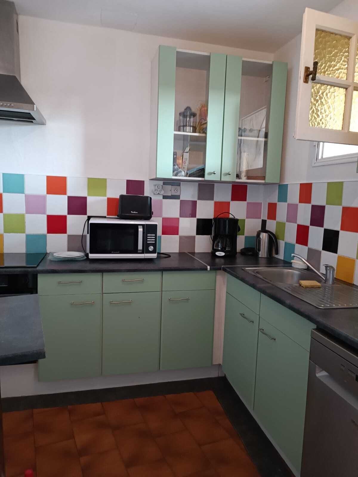 A kitchen with green cabinets, a microwave, a coffee maker, and a sink.