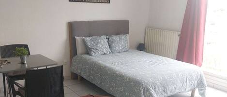 Ein Hotelzimmer mit Bett, Schreibtisch, Stuhl und einer Pendelleuchte.