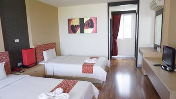 A hotel room with two beds, a TV, a desk, and a bathroom visible through an open door.