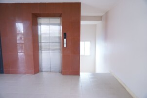 Un ascensor moderno con un panel de control, junto a una puerta con ventana.