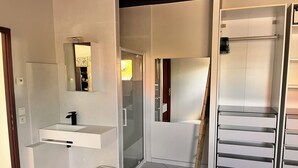 Un baño moderno con lavamanos blanco, espejo y cabina de ducha de vidrio.