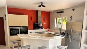 Una cocina moderna con una isla central, electrodomésticos de acero inoxidable y una pared de acento roja.