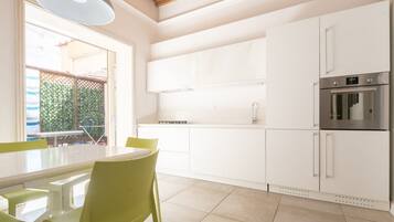 Una cucina moderna con mobili bianchi, un forno in acciaio inossidabile e un'area pranzo con tavolo e sedie.