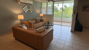 Un salon avec un canapé marron, deux lampes, une table basse et un ventilateur de plafond.