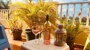 Un balcon avec une table dressée pour deux personnes, agrémenté d’une bouteille de vin, d’un verre et d’une lanterne.