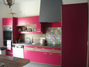 A kitchen with pink cabinets, a wooden countertop, a sink, and a stove. - Saint Malo, large house with garden 15 pers. 400m thermal baths and beach of the furrow (Saint-Malo)