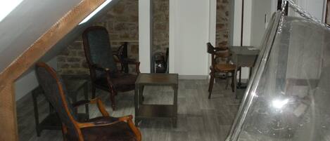 A loft-style room with a stone wall, wooden ceiling beams, and a hanging chair.