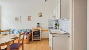 A compact kitchen with a dining area, wooden furniture, and a microwave. - Central Apartment with 1 Bedroom, Ski Locker, Near Lift (Cauterets)