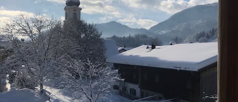 A snow-covered landscape with a church and buildings, a clear sky, and mountains in the background.