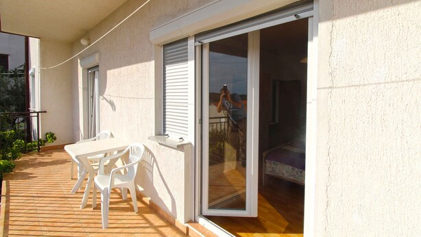 A balcony with a table and chairs, a sliding glass door, and a view of the interior.