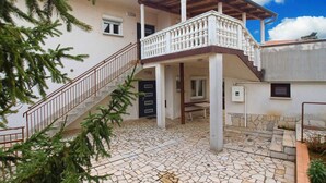 A two-story building with a balcony, stone flooring, and a staircase.