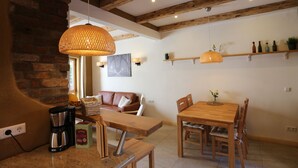 A cozy dining area with a wooden table and chairs, a coffee machine, and a hanging light fixture. - 2017 ecologically renovated, high quality furnished cottage with yard. (Lüneburg)