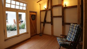 A room with a large window, a dartboard, a ladder, and a plaid chair. - 2017 ecologically renovated, high quality furnished cottage with yard. (Lüneburg)