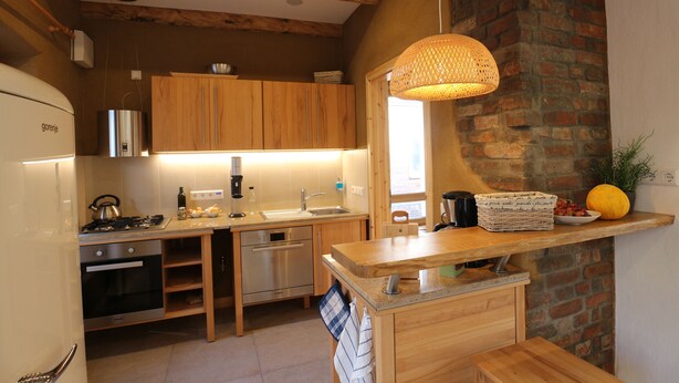 A modern kitchen with wooden cabinets, stainless steel appliances, and a hanging light fixture. - 2017 ecologically renovated, high quality furnished cottage with yard. (Lüneburg)