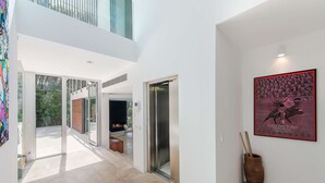 A modern interior with a glass door leading to a balcony, a wooden bench, and a framed artwork on the wall.