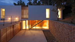 A modern building with a flat roof, large windows, and a staircase leading to an upper level.