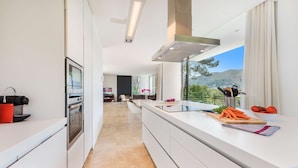 A modern kitchen with a large island, stainless steel appliances, and a view of the outdoors.