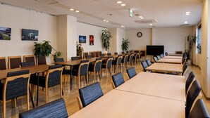 A conference room with multiple tables and chairs, a clock, and wall-mounted artwork.