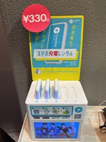 Estación de alquiler de baterías portátiles con código QR para escanear, puertos de carga y pantalla mostrando un código QR para descargar la aplicación.