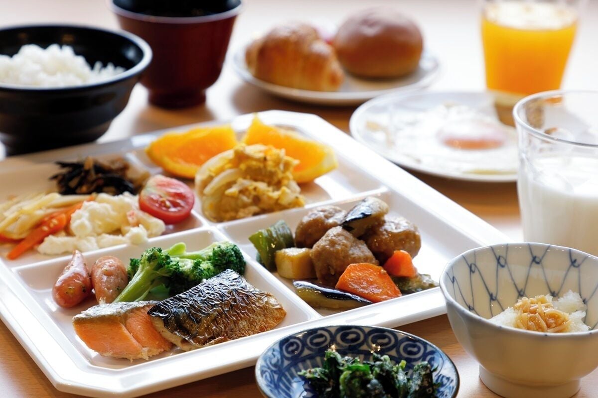 Una bandeja con varios platos que incluyen pescado, verduras y arroz.