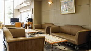 A hotel lobby with seating, a television, and a framed picture on the wall.