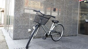 Een fiets staat tegen een gevel met een ruwe steenbekleding.