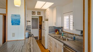 A kitchen with a marble countertop, white cabinets, a built-in oven, and a window with blinds.