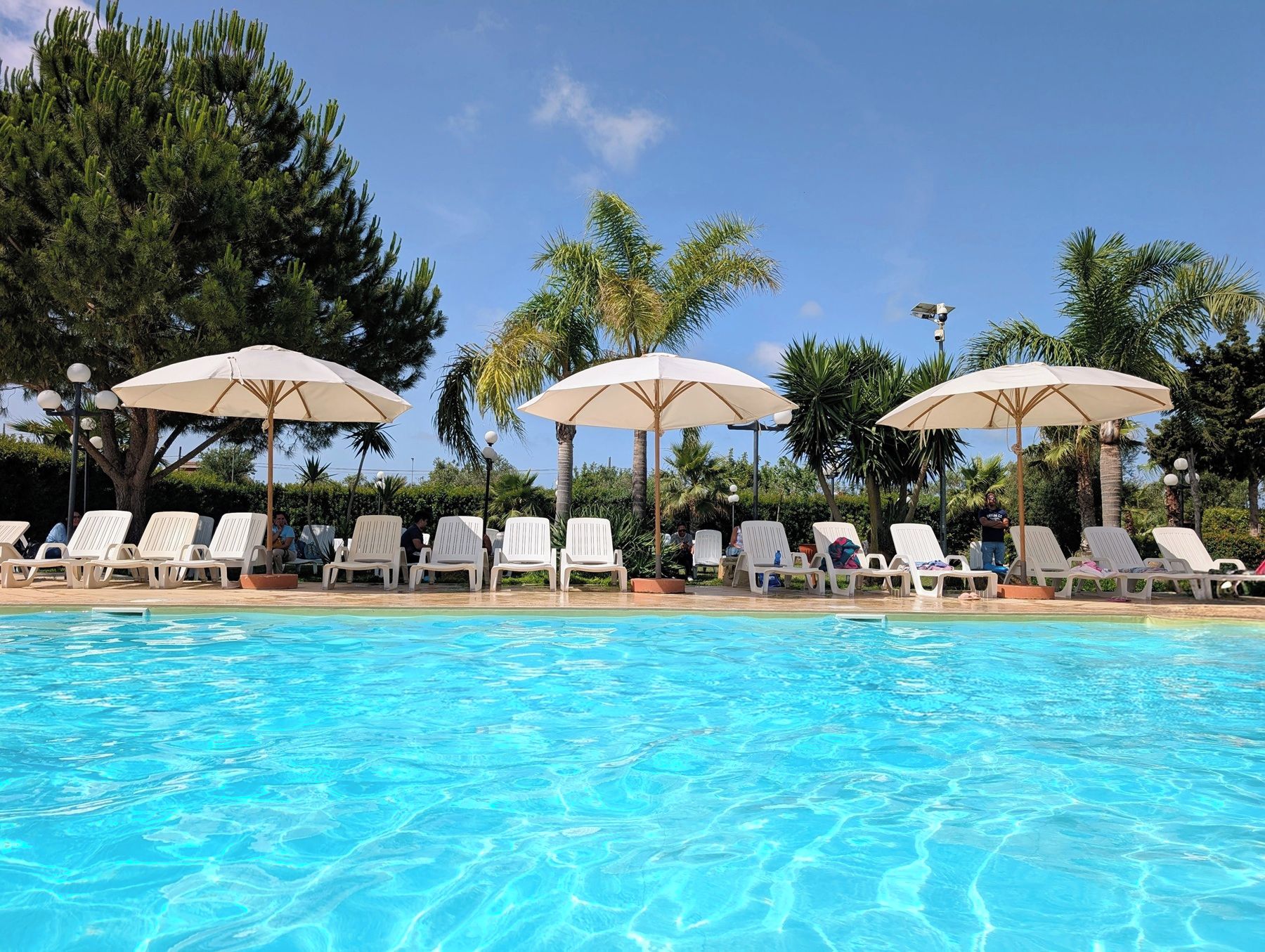 A swimming pool with lounge chairs and umbrellas.