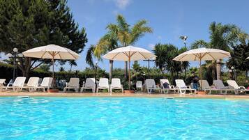 A swimming pool with lounge chairs and umbrellas.
