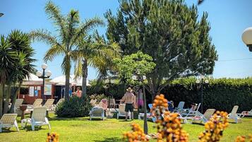 A garden area with lounge chairs and a small building, likely a poolside or spa area.