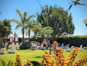 A garden area with lounge chairs and a small building, likely a poolside or spa area. - Lilybeo Village - Welcoming Residence (Marsala)
