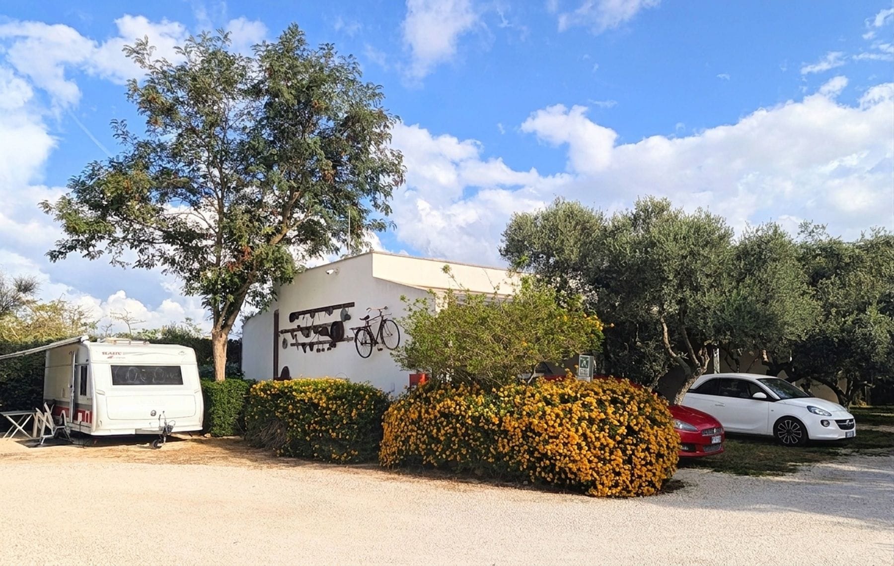 A caravan parked beside a building with a bicycle and a car.