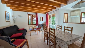 A cozy room with a sofa, dining table, chairs, and a fireplace. - Quiet house in exceptionally beautiful Holiday Resort **** in Dordogne-Lot (Gavaudun)