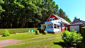 A red and white house with a large garage, surrounded by a well-maintained lawn and hedges. - Holiday home FLOW DREAM - Holiday home FLOW DREAM (Göhren-Lebbin)