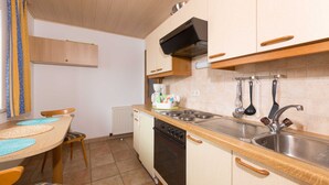 Une cuisine compacte dotée de meubles en bois, d’une cuisinière, d’un évier et d’un coin repas avec une table et des chaises.