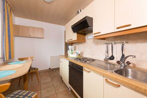 Una cucina funzionale con mobili in legno, un piano cottura, un lavello e un'area pranzo con tavolo e sedie.