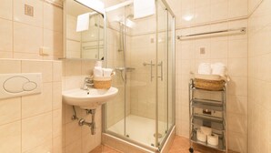 Une salle de bain moderne dotée d’une douche à parois de verre, d’un lavabo avec un panier contenant des articles de toilette et d’un porte-serviettes avec des serviettes.
