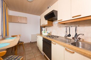 A compact kitchen with a stove, sink, and wooden cabinets.