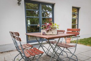 A wooden table with metal chairs and a planter box with flowers. - Apartment Hühnergott - Kölp - forest and sea(h)r (Loddin)