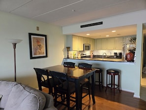 A modern kitchen with light green cabinets, a stainless steel sink, and a dining area with a wooden table and chairs.